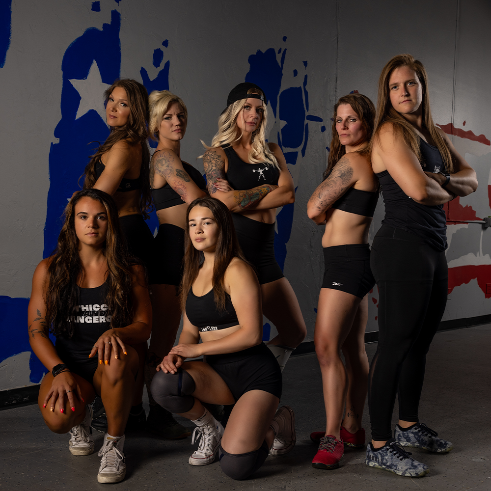 Group of women posing in athletic wear against a Limitless american flag background