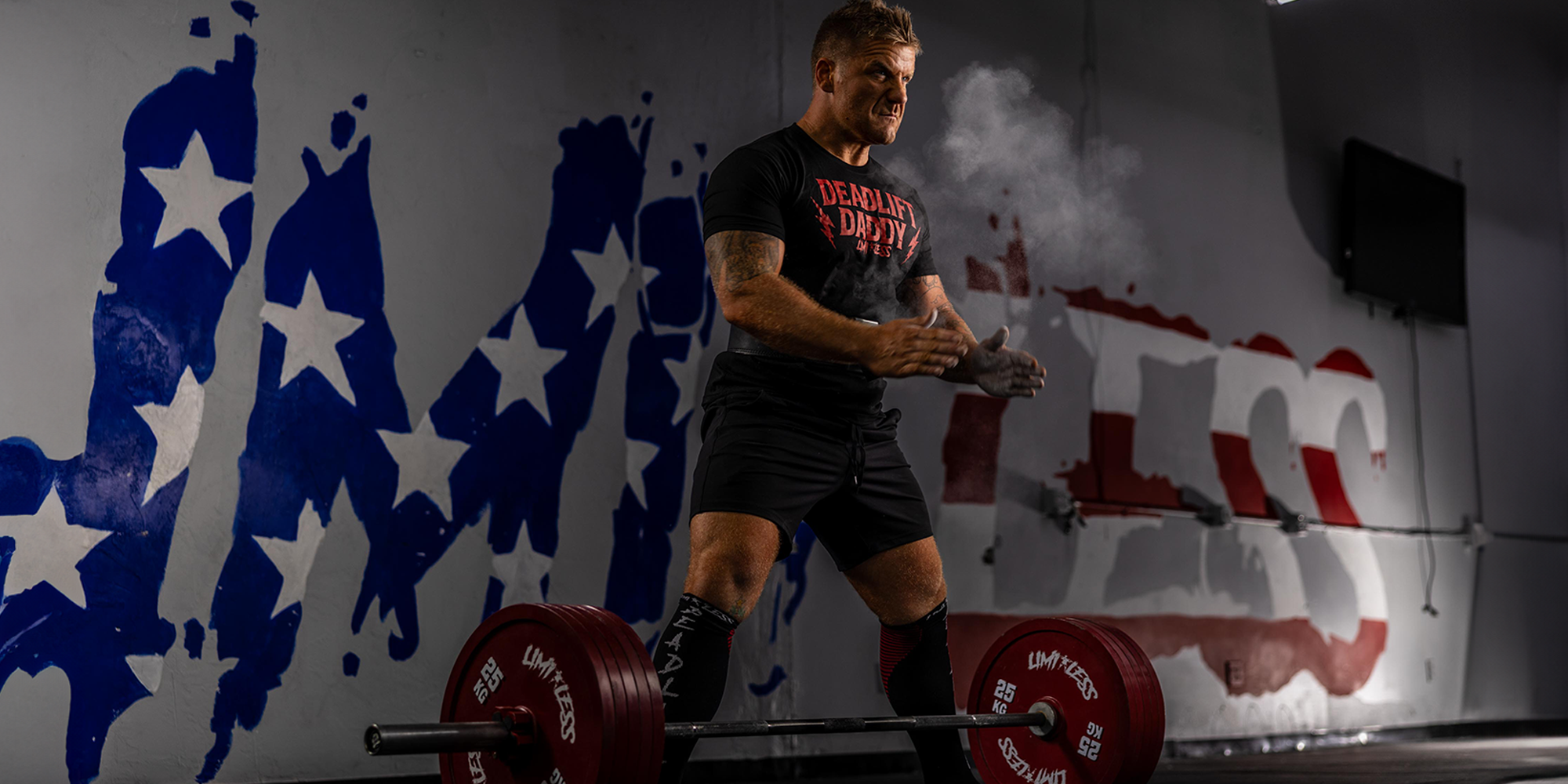 Quintin Meyer lifting weights with a Limitless patriotic mural in the background