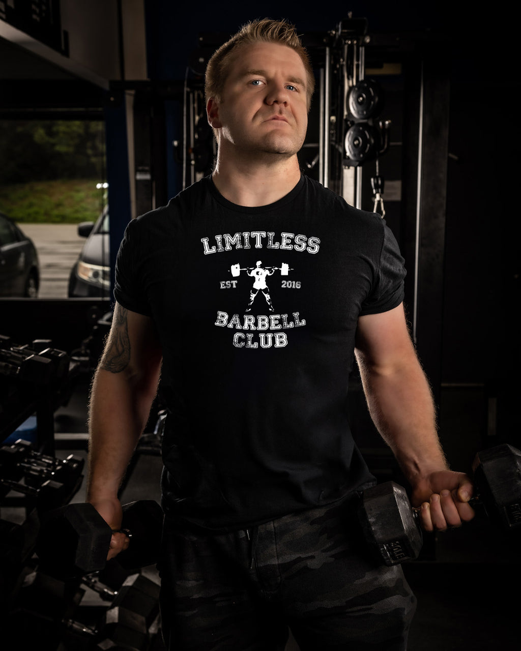 Man wearing a black t-shirt with 'Limitless Barbell Club' text in a gym setting