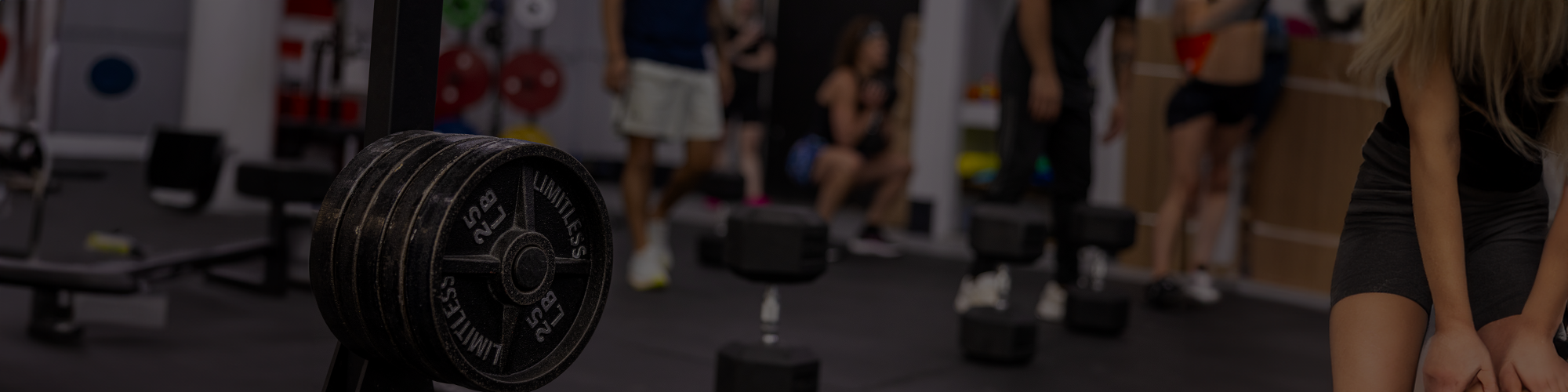 Person lifting weights in a gym setting with other people in the background