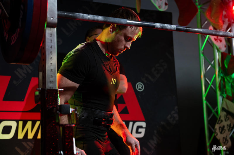 Person lifting weights in a gym setting with visible branding.  USA Powerlifting and Limitless Powerlifting
