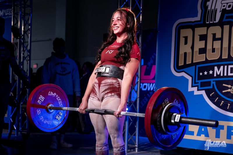 Woman lifting a barbell with weights at USA Powerlifting Midwest Regionals hosted by Limitless Powerlifting