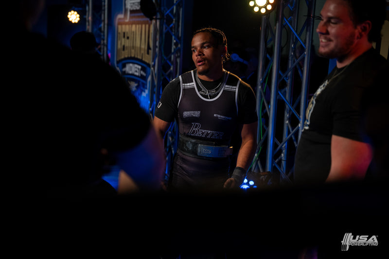 Two men standing in a dark indoor setting with blue lighting