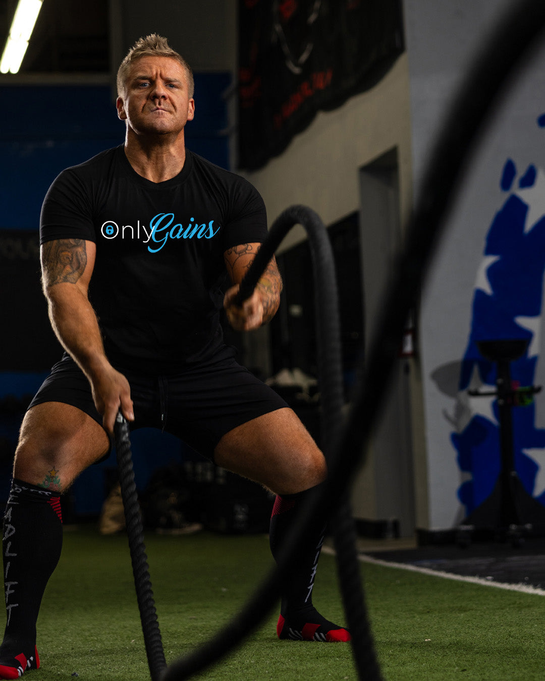 Man in a gym using battle ropes with 'onlyGains' t-shirt
