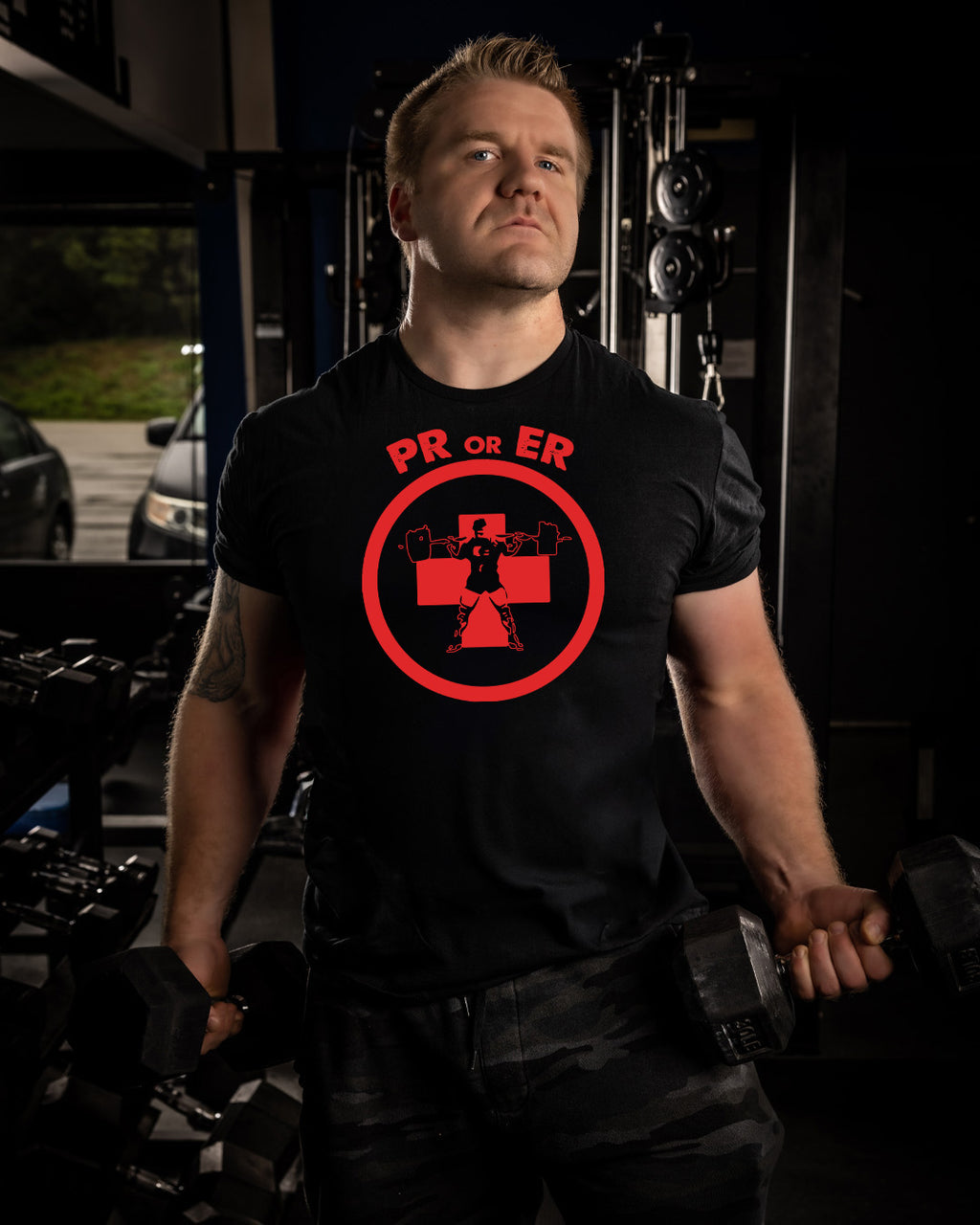 Man wearing a black t-shirt with a red logo in a garage setting