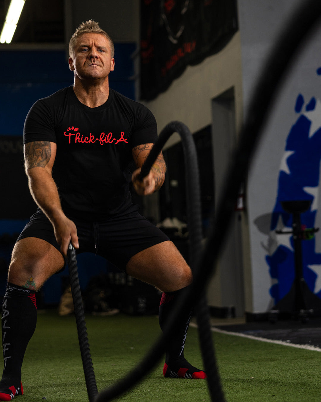 Man exercising with battle ropes in a gym setting