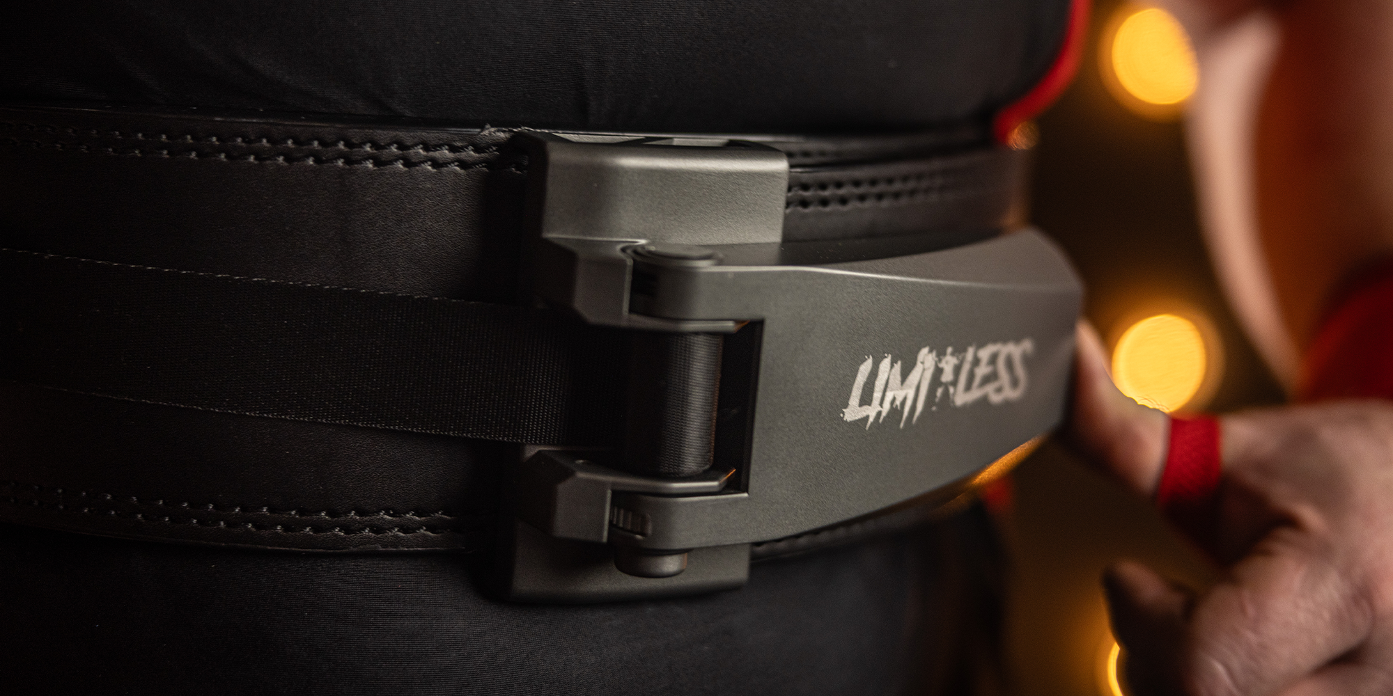 Close-up of a black belt with a metallic buckle, featuring the brand 'Limitless'.