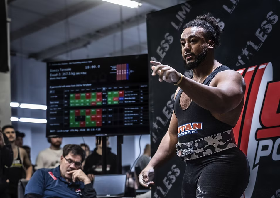 Athlete in a weightlifting competition with spectators and digital display in the background